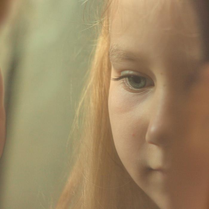 cara d'una nena amb una mirada neutra veient-se reflexada en un vidre