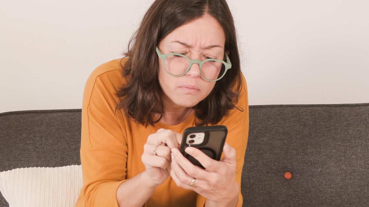 una noia amb ulleres mirant el mòbil amb detall
