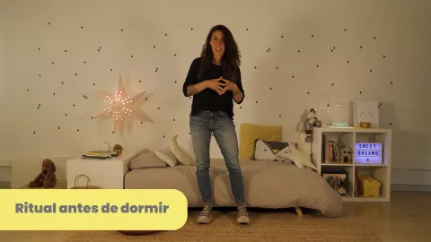 Cris Moe de pie en una habitación infantil explicando el ritual antes de dormir del bebé, lección del curso “Quiero dormir”.