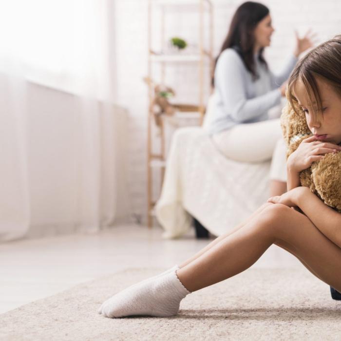 nena trista amb peluix i pares de fons discutint